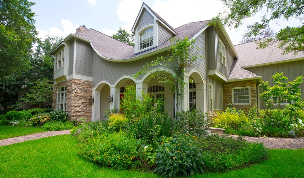 A well-maintained spring landscape in front of a multi-story home.